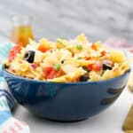 closeup of a blue bowl filled with summer pasta salad