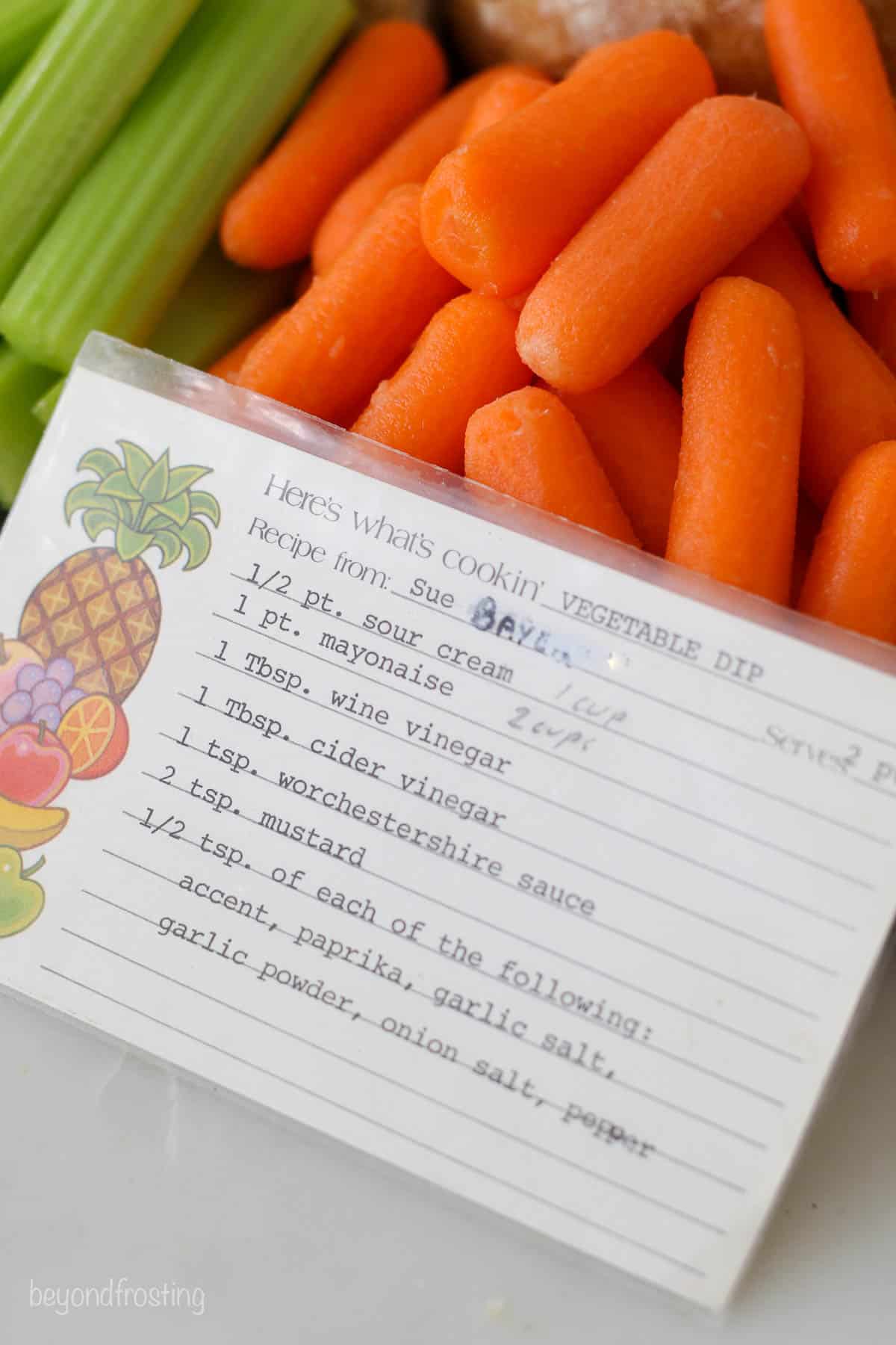 A hand-written recipe card in front of carrots and celery