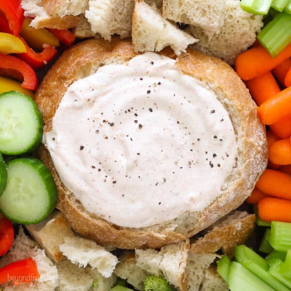 Overhead view of a veggie plate with a bread bowl of dip in the center