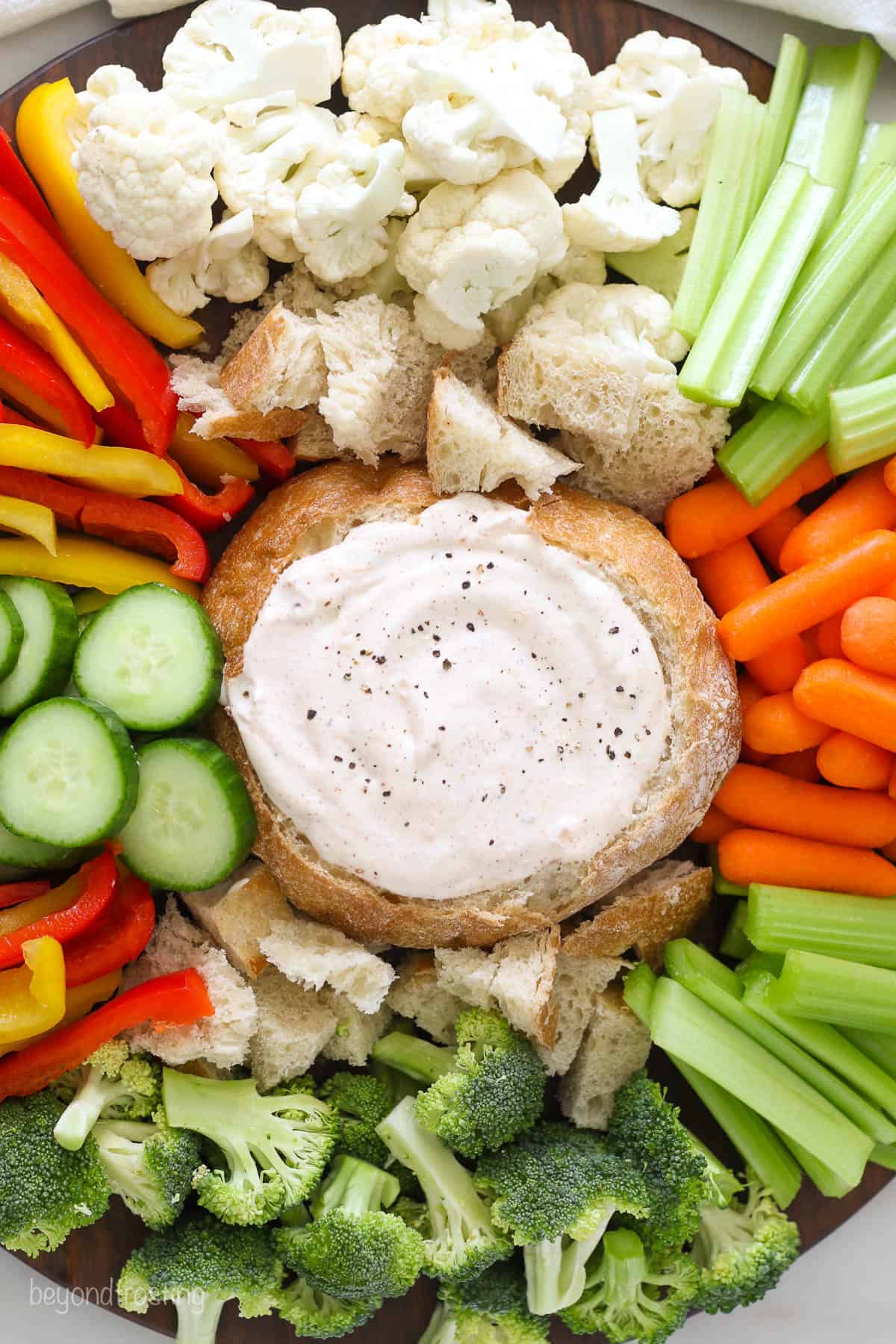 Overhead view of a veggie plate with a bread bowl of dip in the center