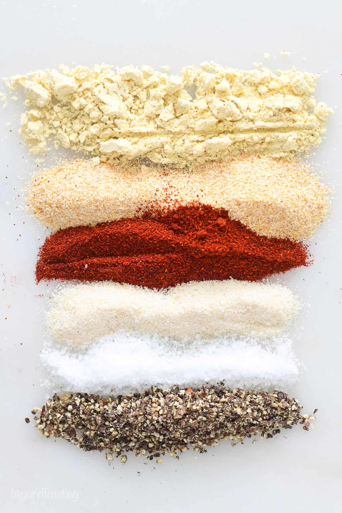 The spices used in veggie dip laying on a cutting board in rows