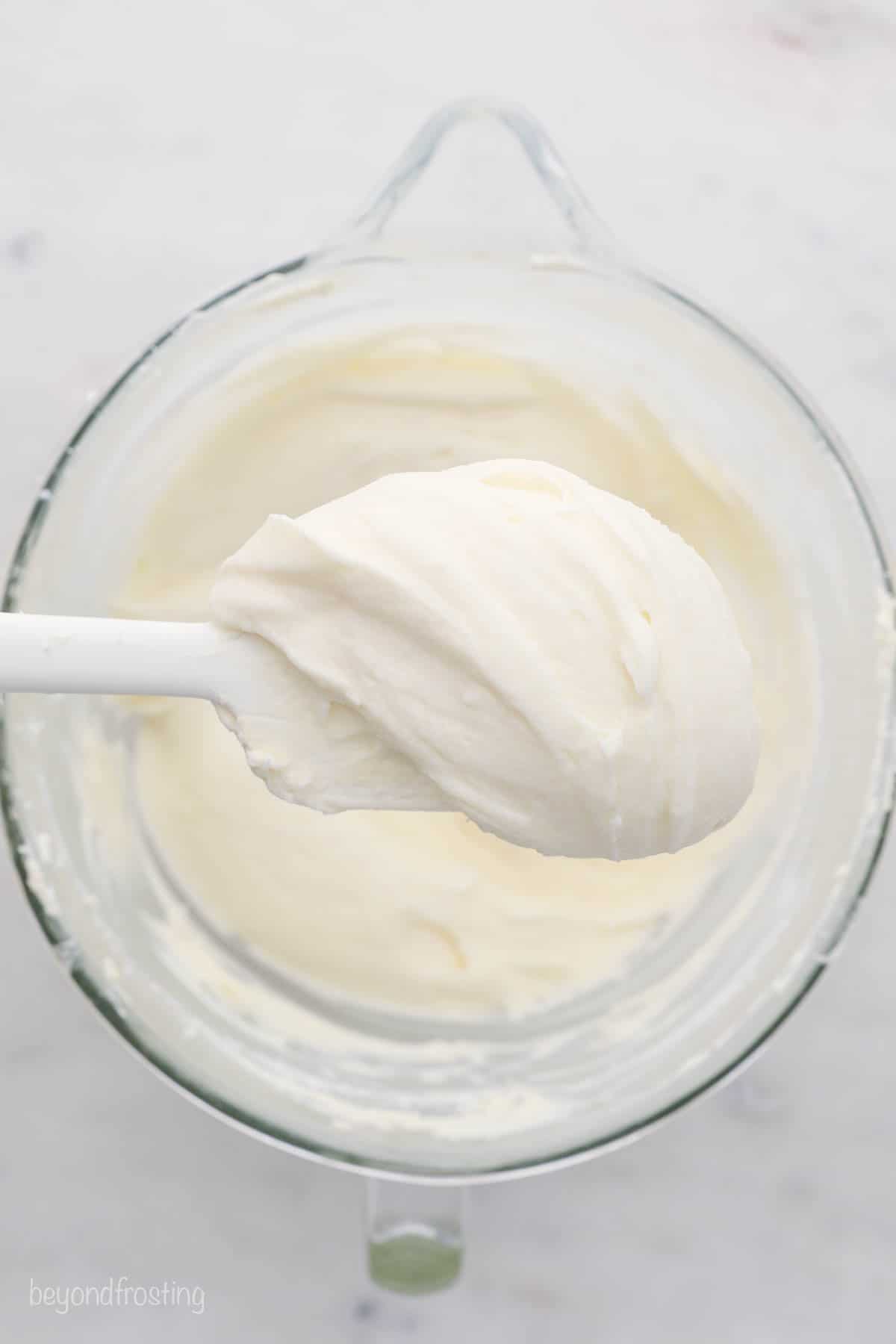 Cream cheese frosting on a spatula over a mixing bowl of it
