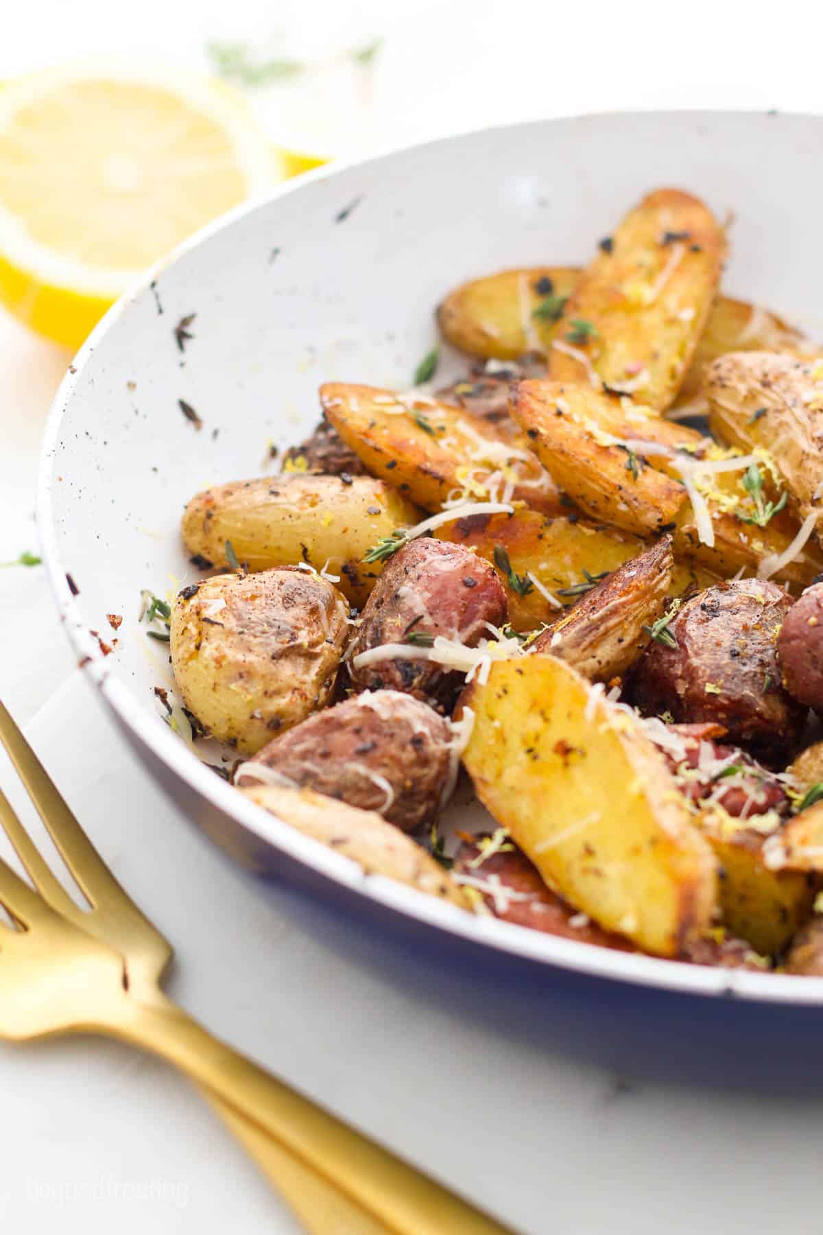 shot of a pile of roasted potatoes in a bowl next to a gold fork