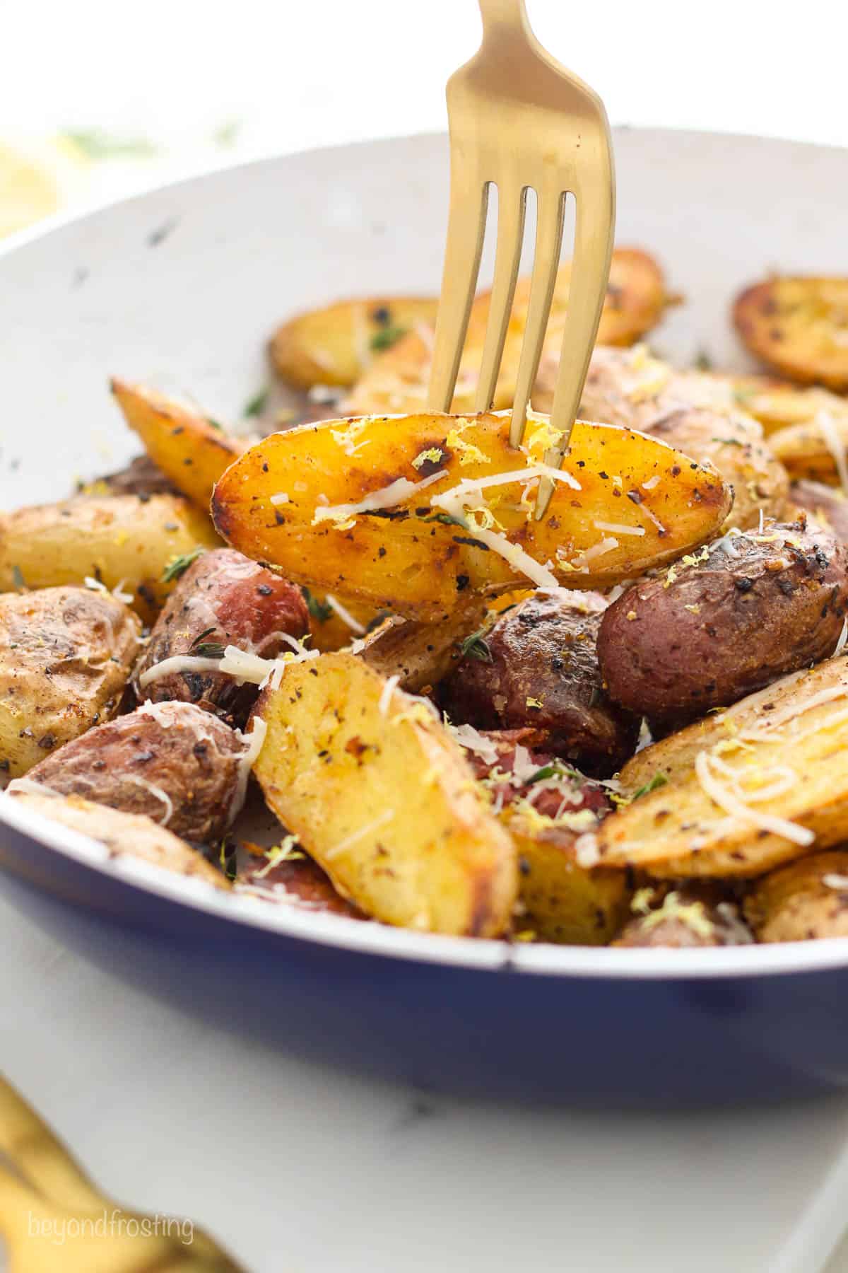 fork stuck into a roasted potato on a plate