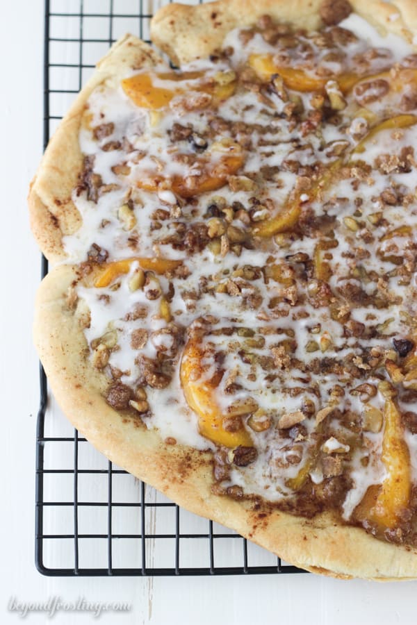 a whole peach streusel pizza on a cooling rack
