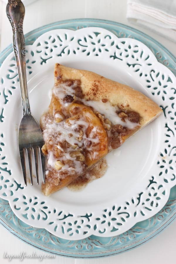 overhead of a slice of peach streusel pizza on a white plate with a fork