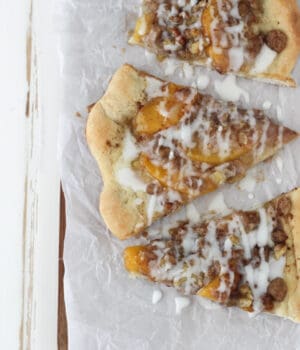 overhead of three slices of peach streusel pizza on a piece of parchment paper