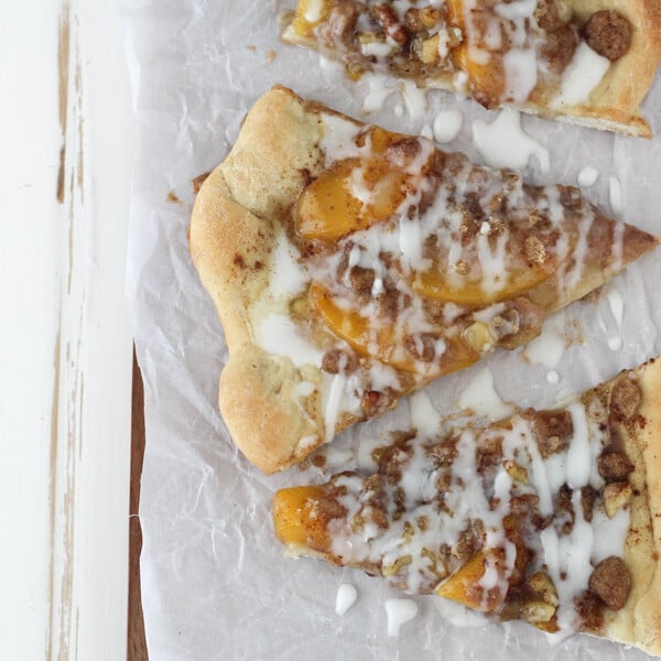 overhead of three slices of peach streusel pizza on a piece of parchment paper