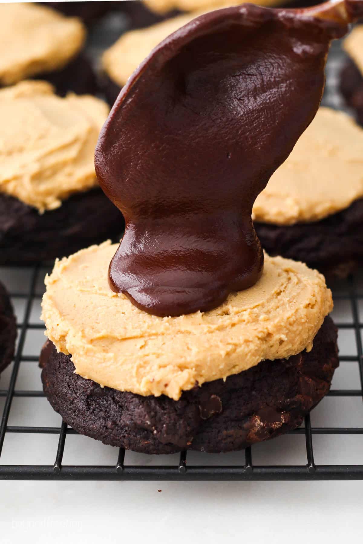 Chocolate ganache being spooned on top of a layer of peanut butter filling