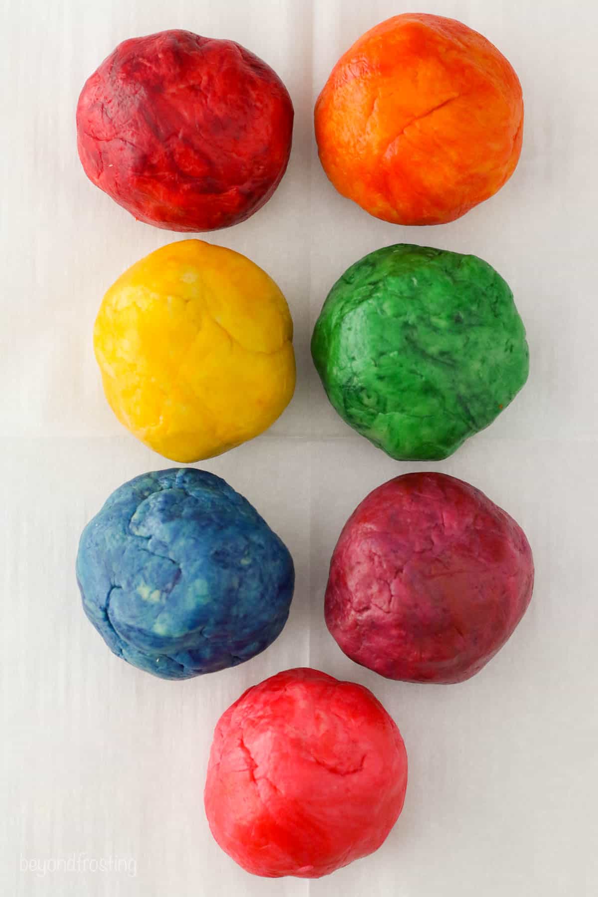 Seven balls of dyed sugar cookie dough
