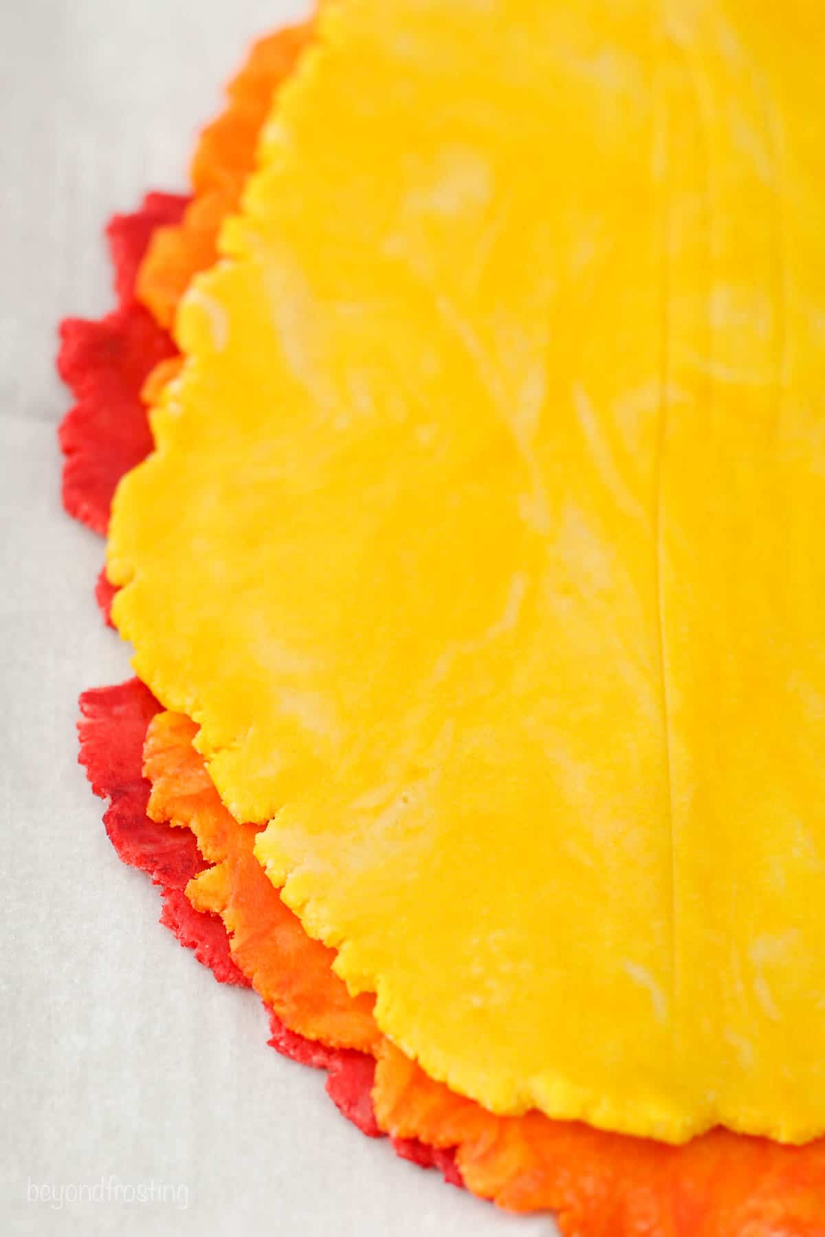 Layers of red, orange, and yellow sugar cookie dough rolled out