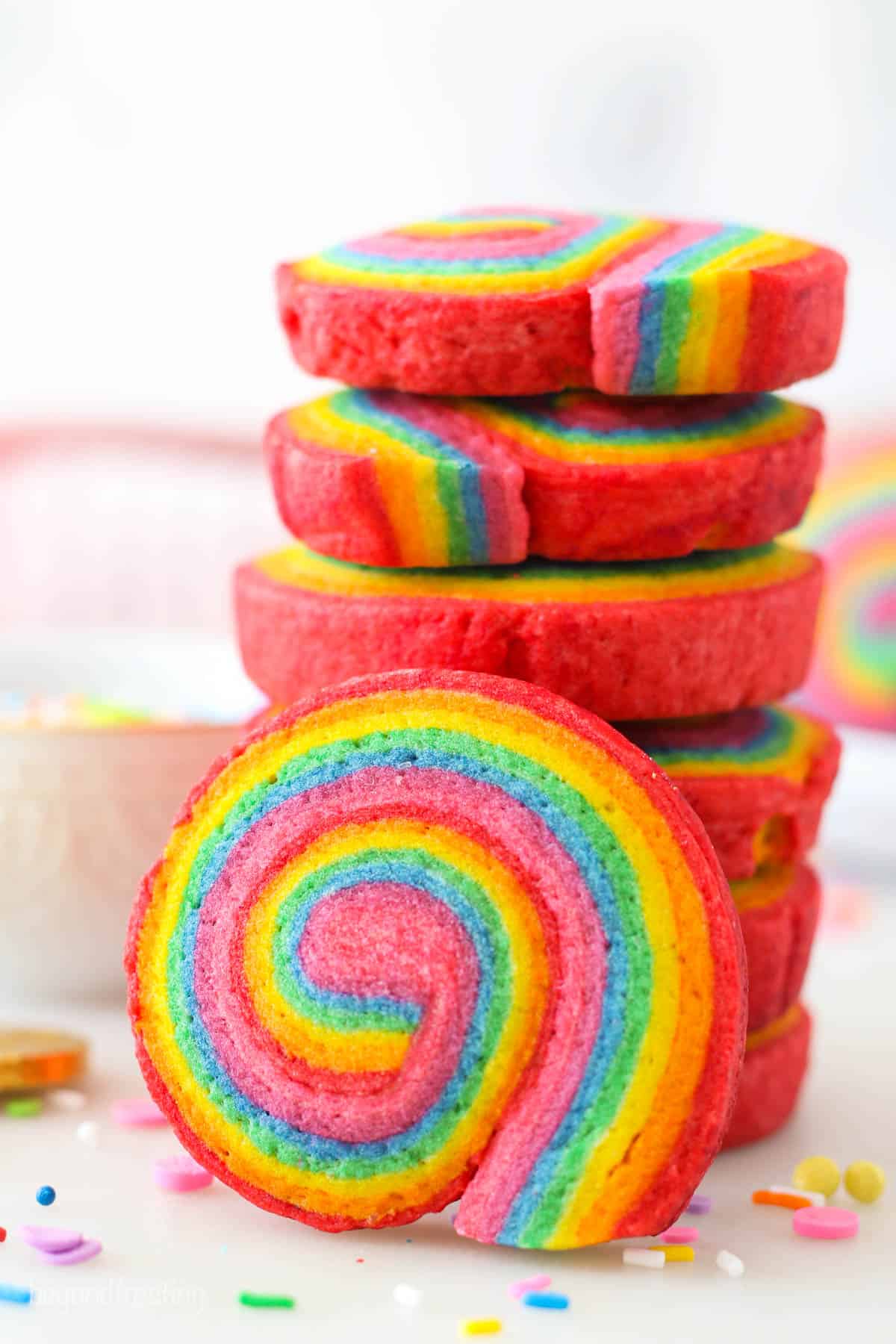 A rainbow cookie leaning against a stack of cookies.
