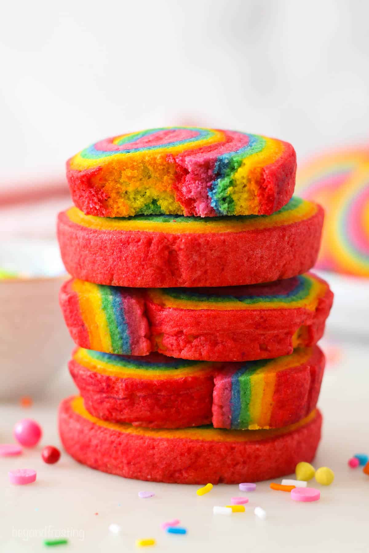 A stack of rainbow cookies with a bite missing from the top cookie.