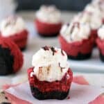 a red velvet cookie cup on a napkin with a bite taken out with other cupcakes in the background