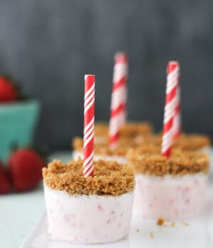 side view of strawberry popsicles standing upright on a white plate