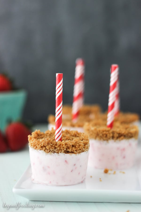 side view of strawberry popsicles standing upright on a white plate