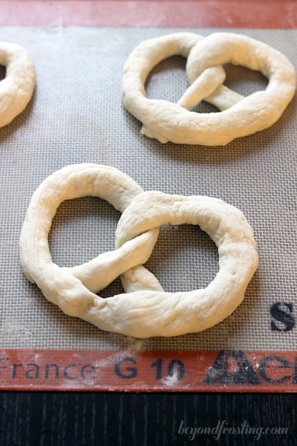 overhead of unbaked soft pretzels on a baking sheet