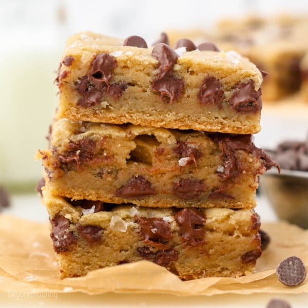A stack of three chocolate chip cookie bars on a piece of parchment paper.