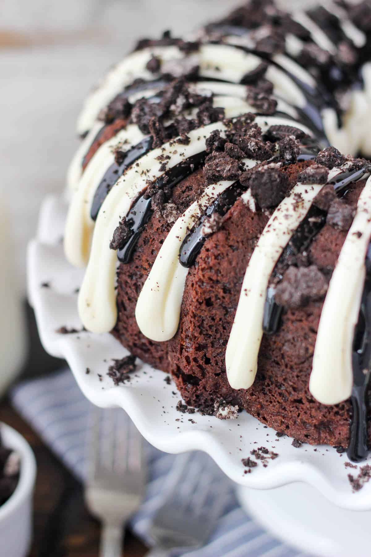 overhead and closeup of an oreo chocolate cheesecake bundt cake on a cake stand