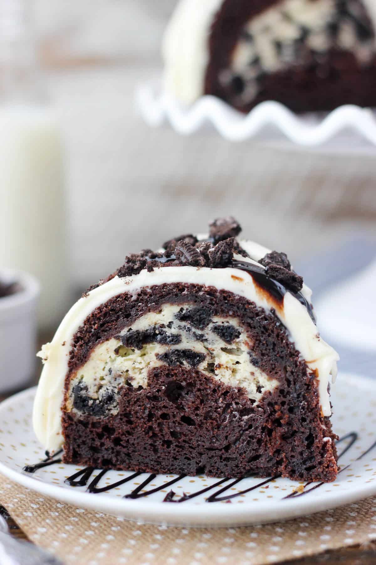 side view of a slice of chocolate cake with oreo cheesecake filling on a white plate