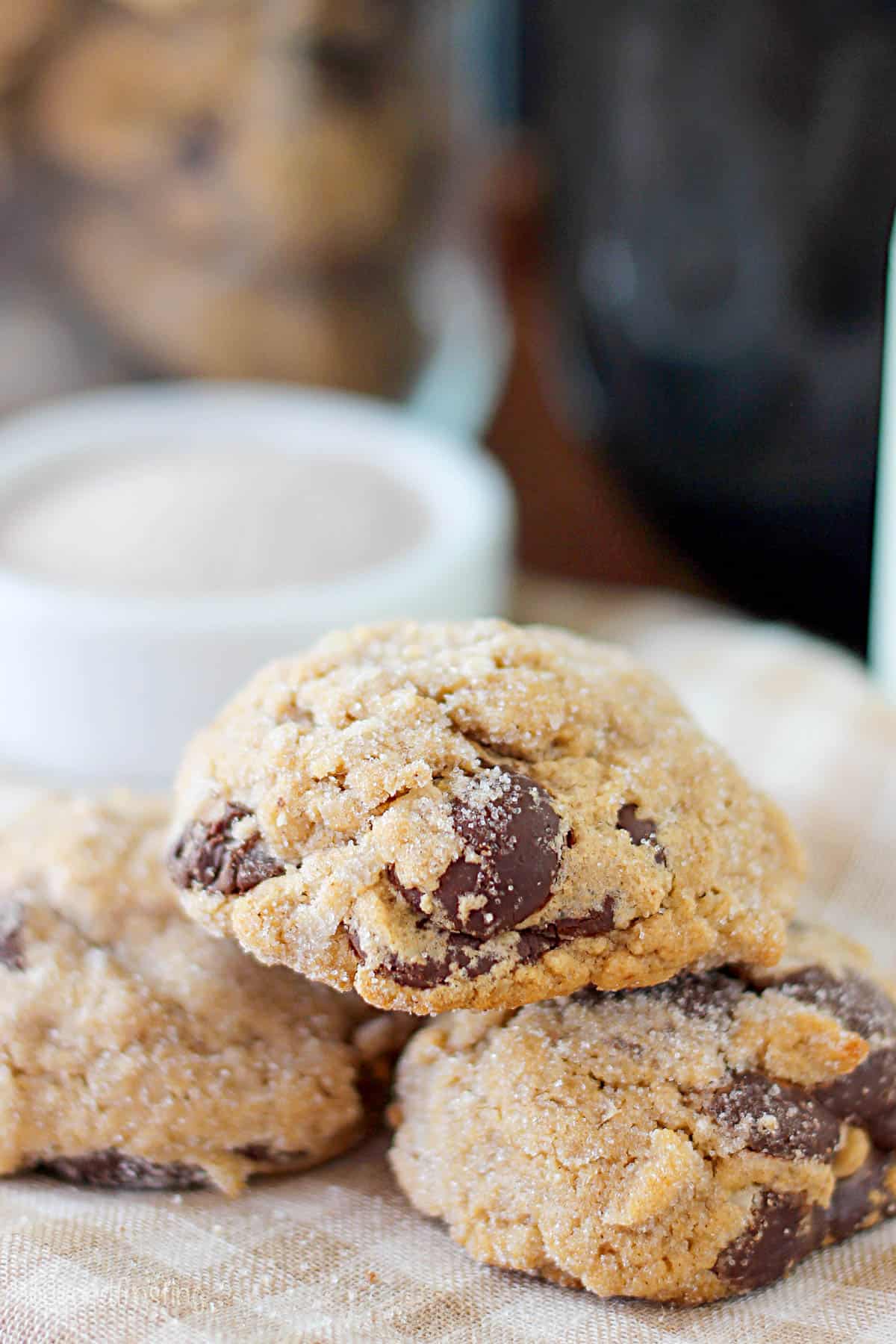 two chocolate chip cookies on a checkered cloth with one stacked on top