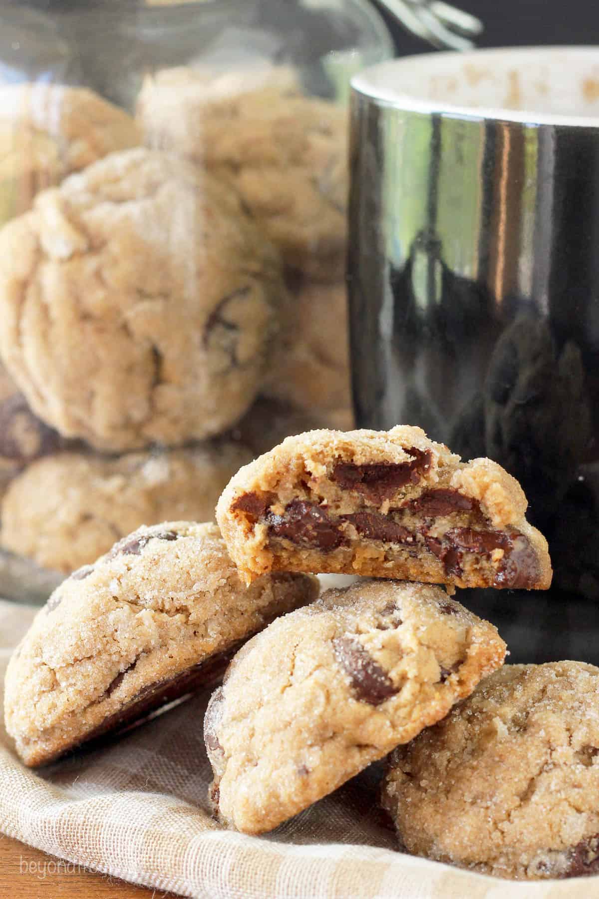 three coconut cookies lined up with half of a cookie stacked on top and a cookie jar in the background