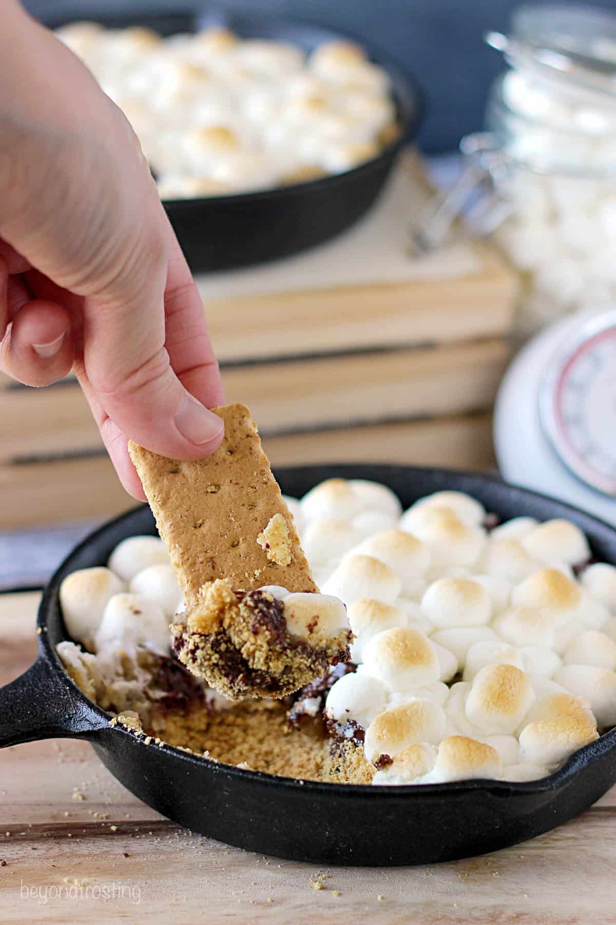 graham cracker being dipped into a skillet filled with cookie dough s'mores dip