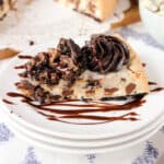 a slice of cookies and cream cake on a stack of white plates