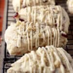 closeup of cranberry scones drizzled with maple glaze lined up on a cooling rack