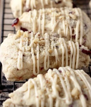 closeup of cranberry scones drizzled with maple glaze lined up on a cooling rack