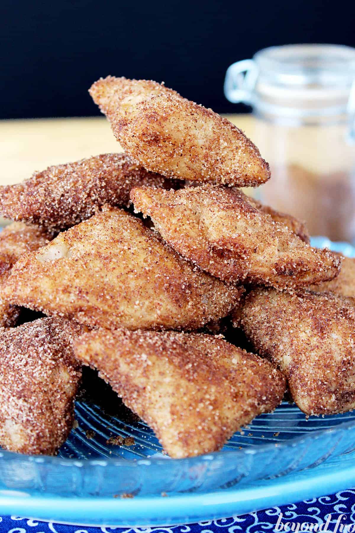 side view of deep-fried apple pie bites piled on a blue plate