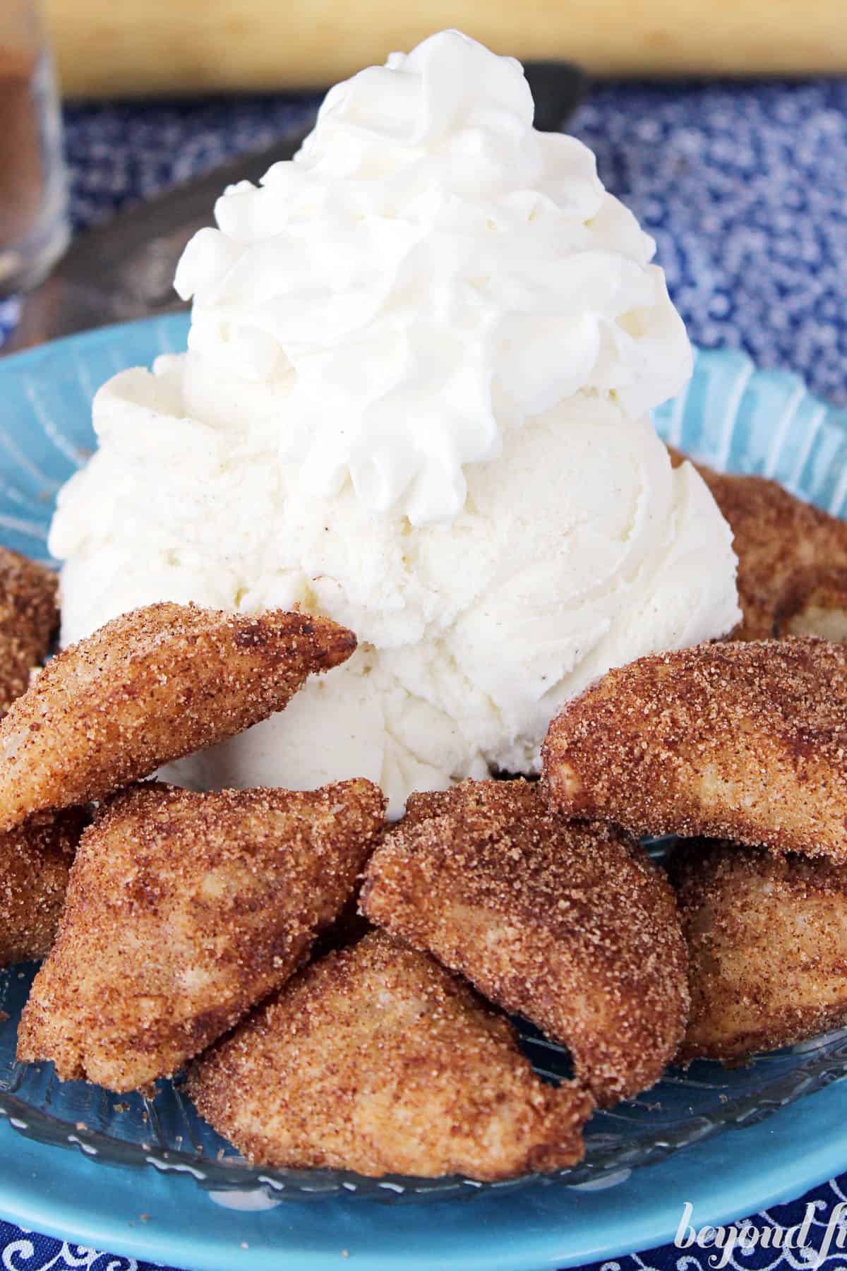 apple pie fritters on a blue plate surrounding a scoop of ice cream