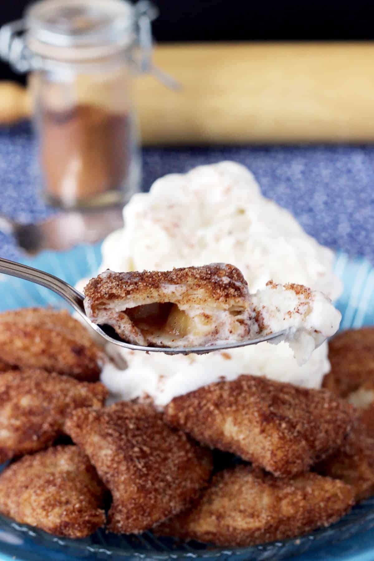 a bite of apple pie bites being held over a plate with more bites