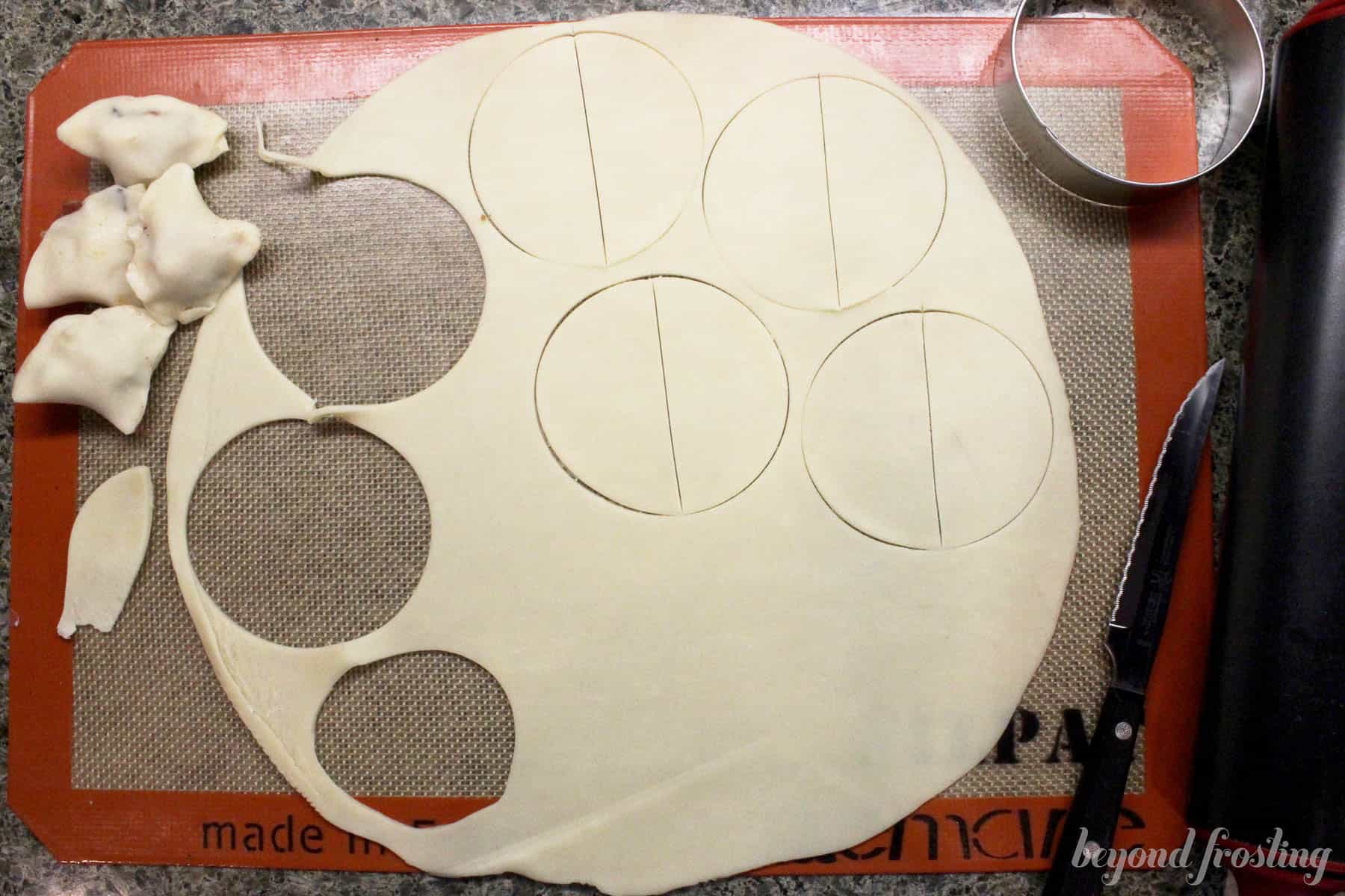 pie crust being cut out on a baking mat overhead