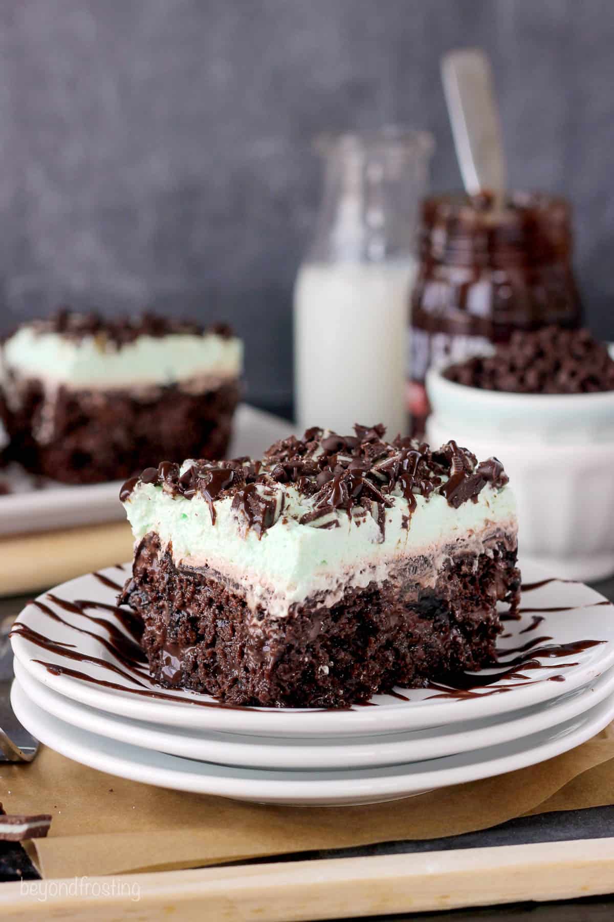 a slice of double chocolate poke cake on a plate with more cake and ingredients in the background