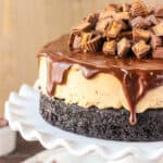 closeup of a Reese's Ice Cream Cake on a cake stand topped with chocolate ganache and peanut butter cups