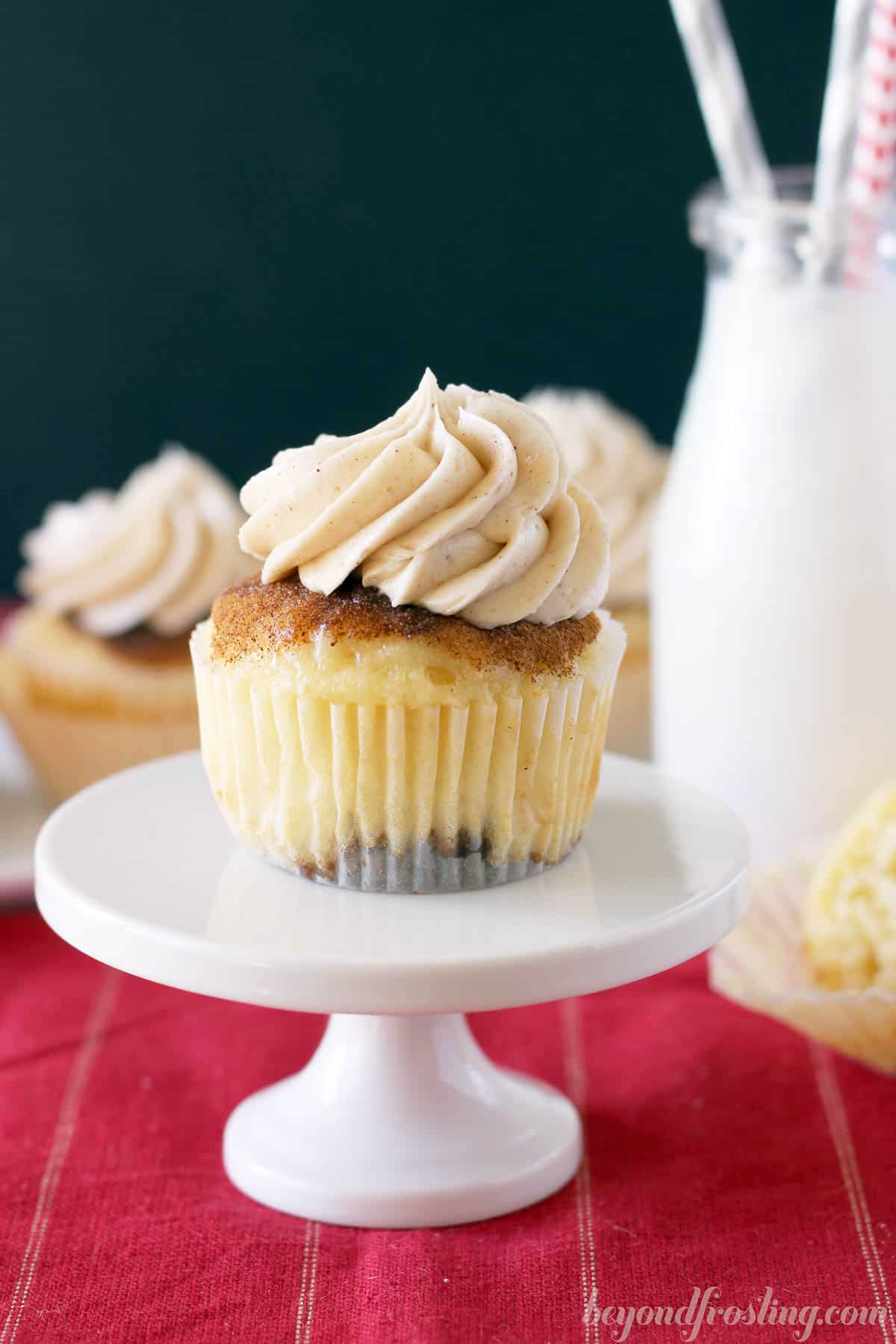 snickerdoodle cupcake on a cupcake stand with a jar of milk in the background