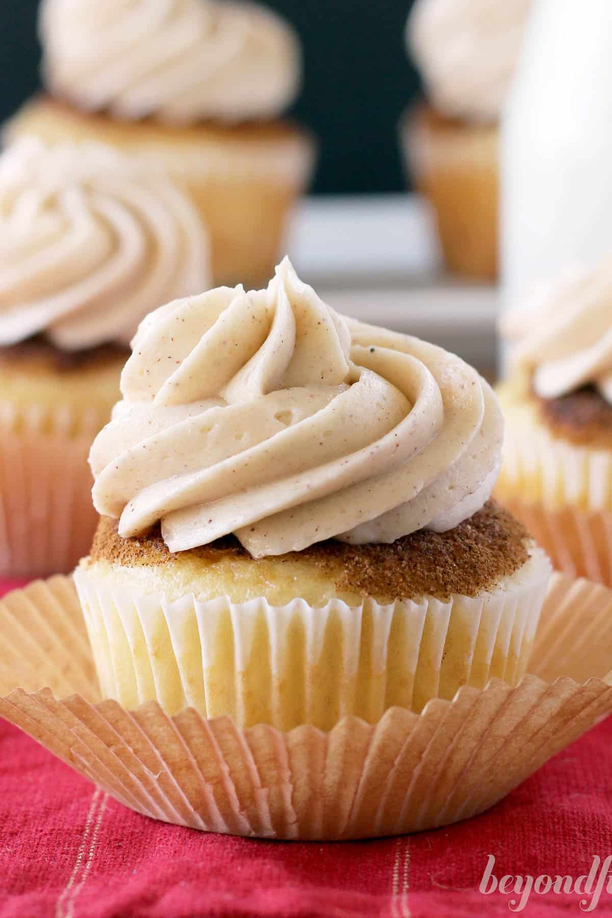 side view of a snickerdoodle cupcake topped with brown sugar cinnamon frosting sitting in a cupcake liner