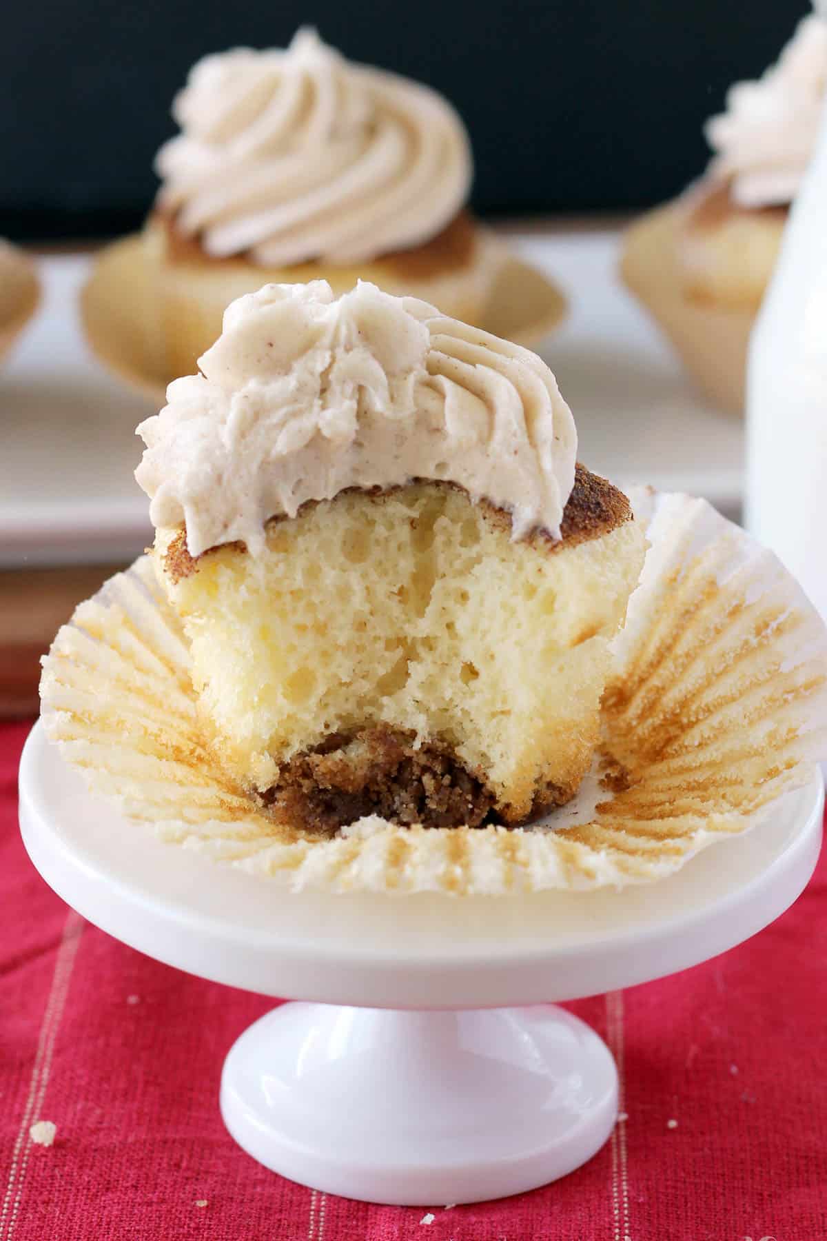 unwrapped snickerdoodle cupcake with a bite taken out sitting on a cupcake stand