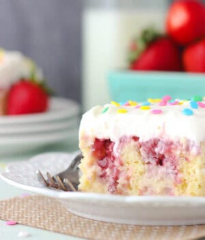 closeup of a slice of strawberry poke cake on a plate