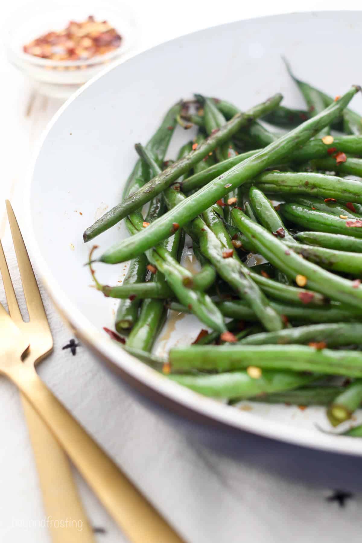 closeup of sautéed green beans piled on a white plate