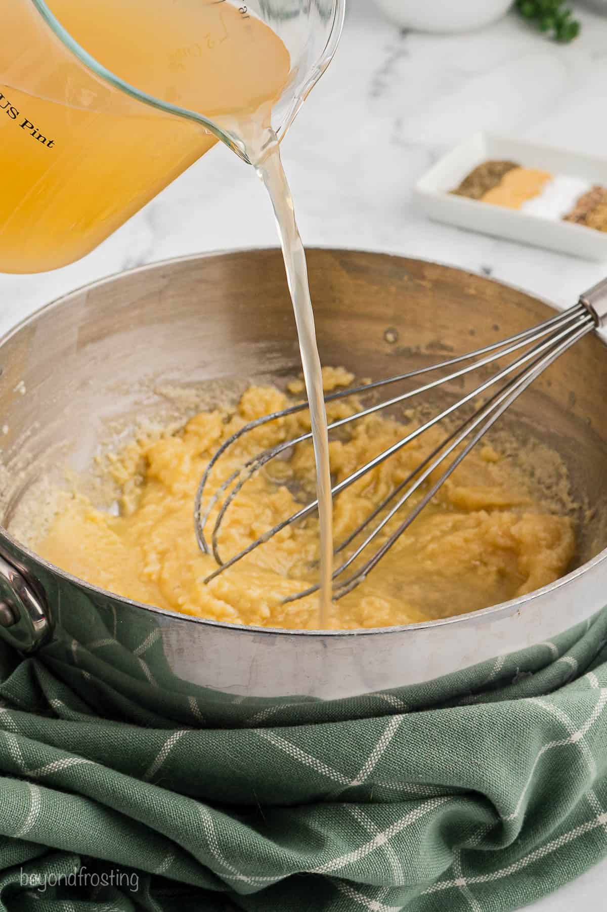 Broth being added to a pan with butter and flour