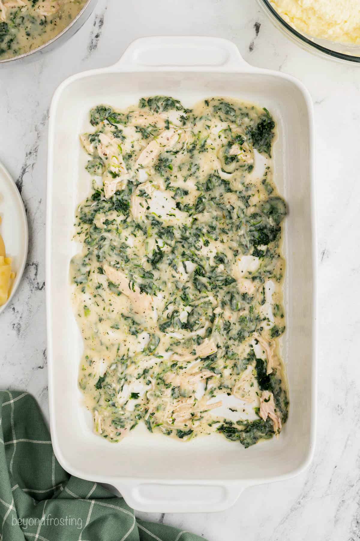 Spinach sauce spread over noodles in a casserole dish