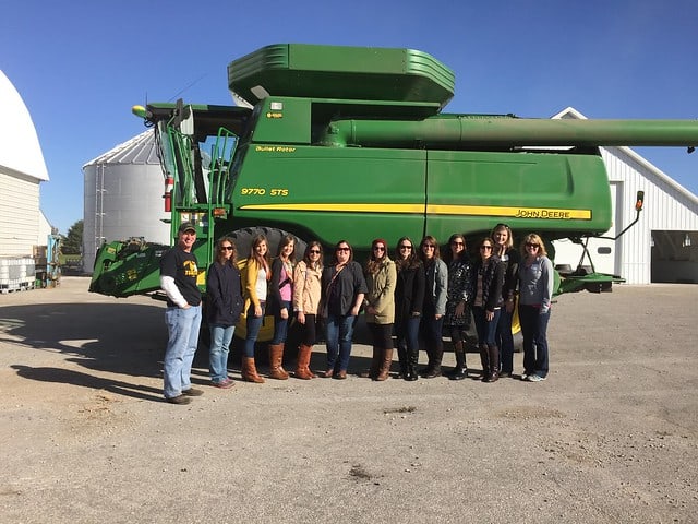A group of ladies posing in front of a green tractor