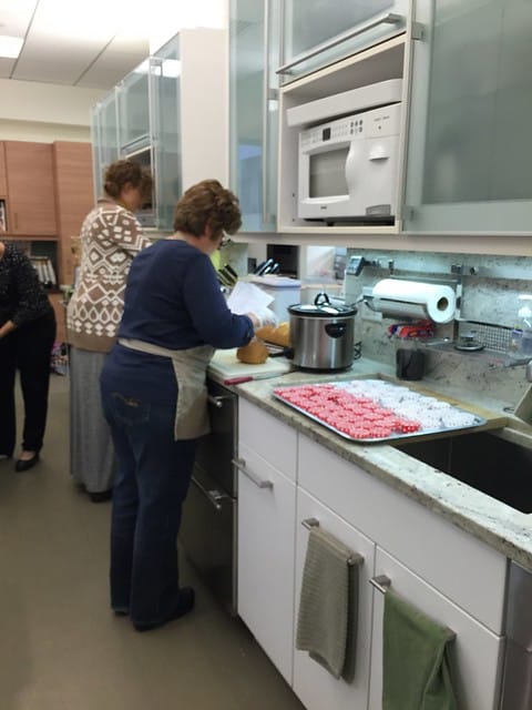 Two ladies working in the test kitchen with a tray of pink and white treats