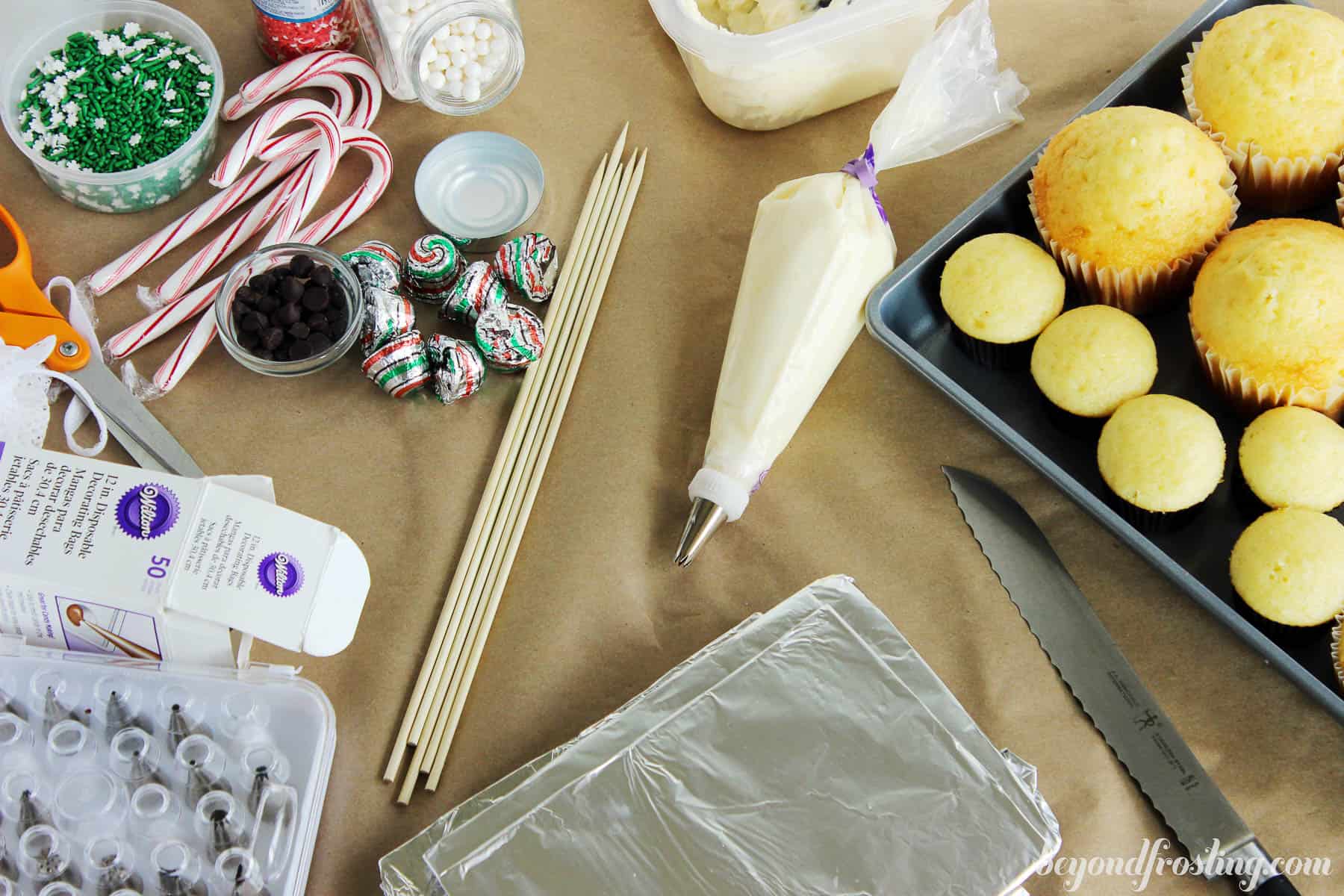 overhead of cupcake snowman decorations next to a pan full of baked cupcakes