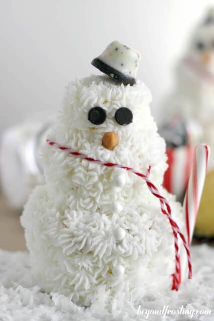 a cupcake snowman decorated with a red and white scarf
