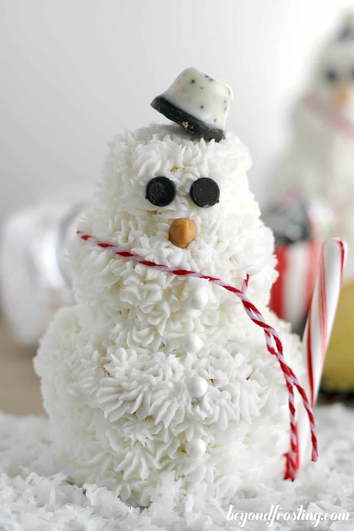 a cupcake snowman decorated with a red and white scarf