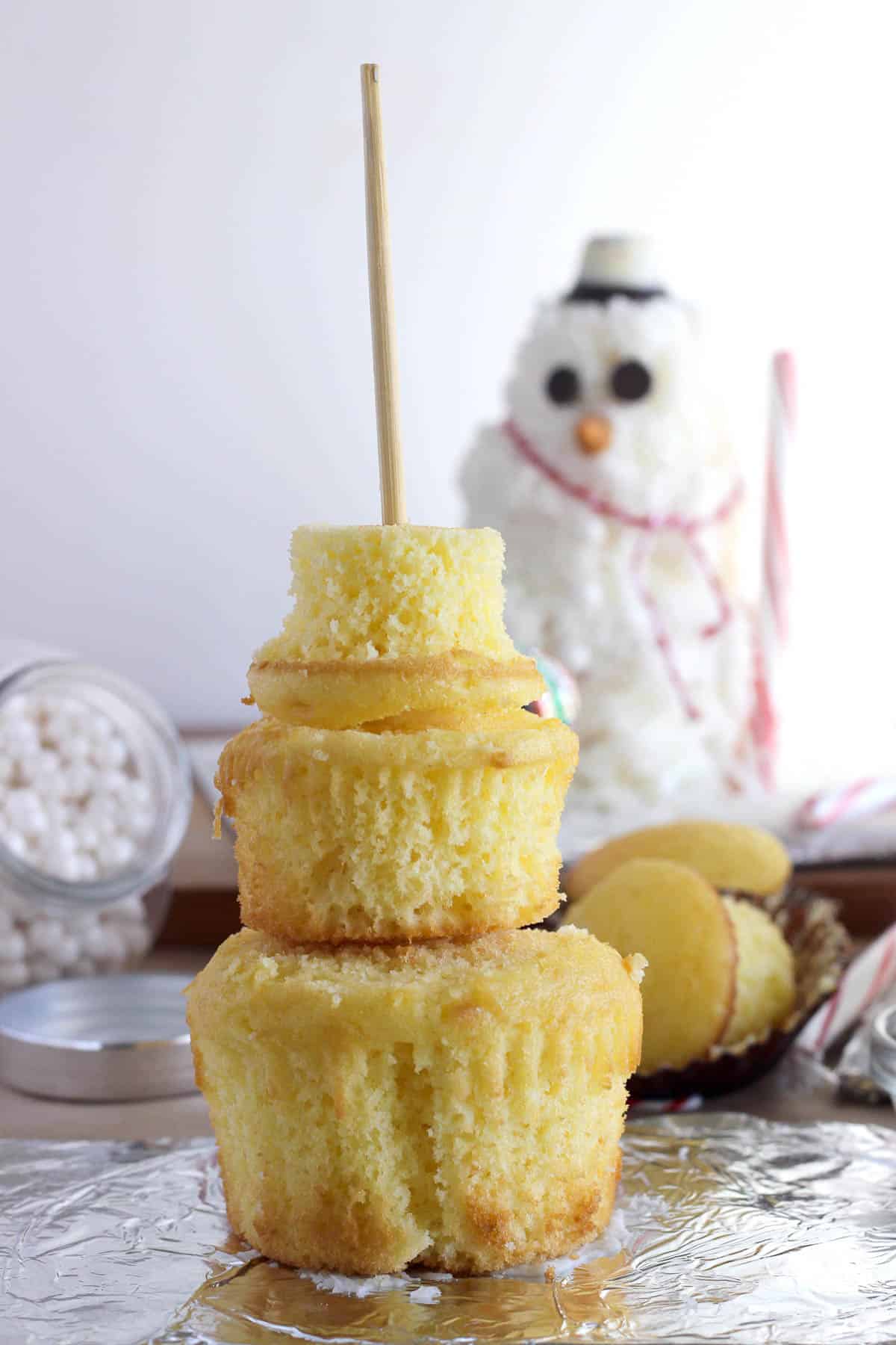 three cupcakes of varying sizes stacked to form the base for a cupcake snowman