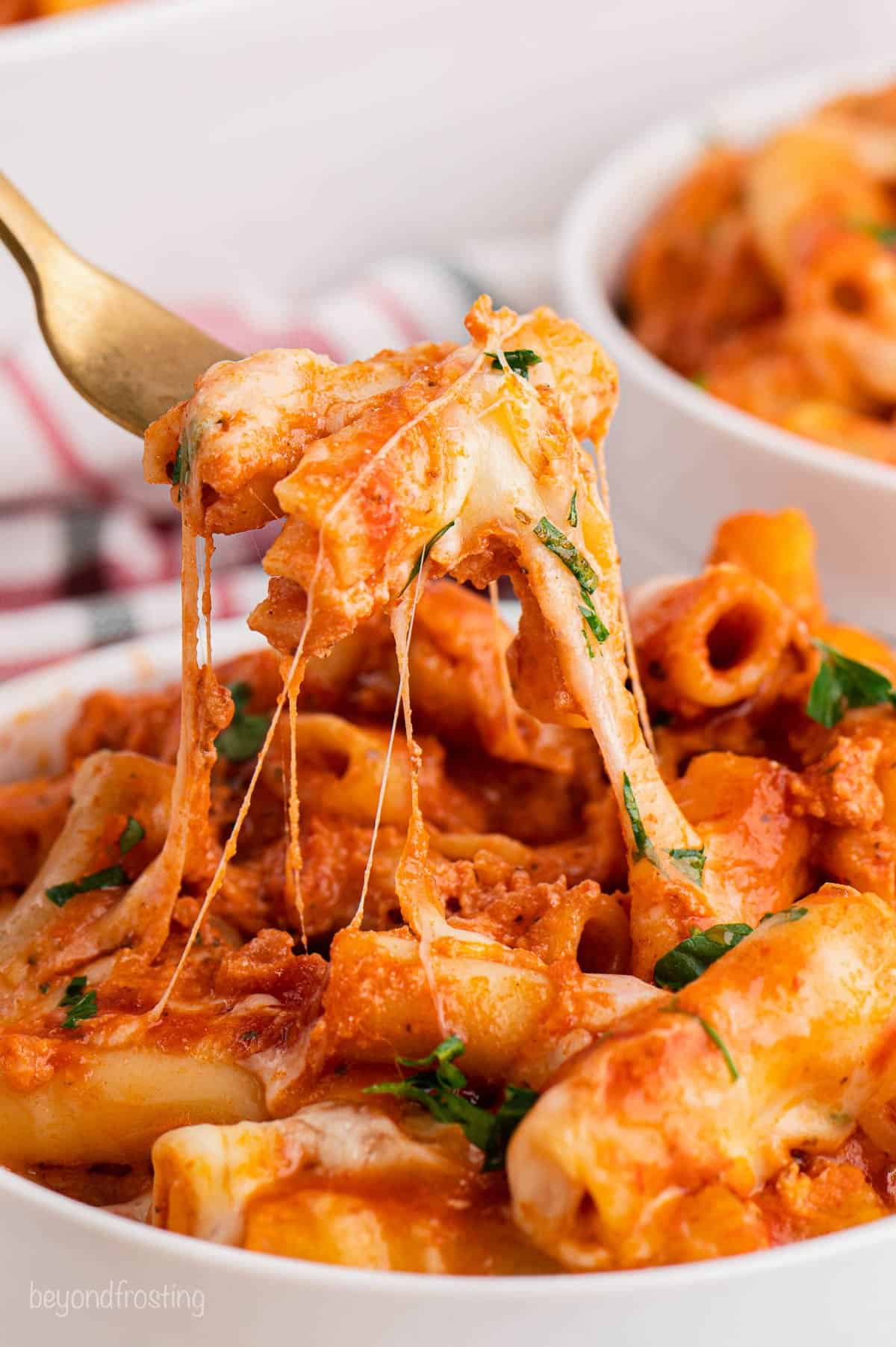 A forkful of baked ziti over a bowl